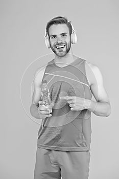 Stay hydrated when training. Happy guy point finger at water bottle. Thirsty athlete in sportswear. Thirst and water