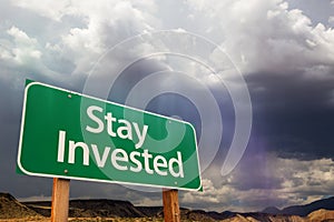 Stay Invested Green Road Sign Over Dramatic Clouds and Sky