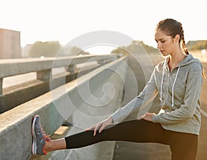 Stay limber and focused. a young female jogger stretching on the road before a run.