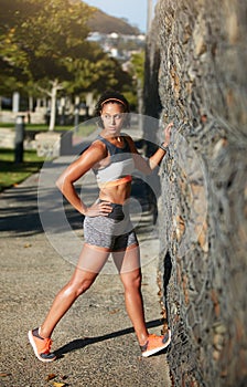 Stay limber. Full length shot of an attractive young woman stretching before a run through the city.