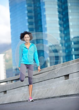 Stay limber and quick. a young female jogger stretching on the street before a run.