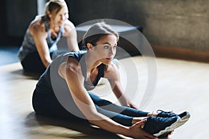 Stay loose. Stay active. Full length shot of two attractive young women stretching before their workout in the gym.