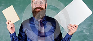 Stay modern with technology. Teacher bearded hipster holds book and laptop. Choose right teaching method. Teacher