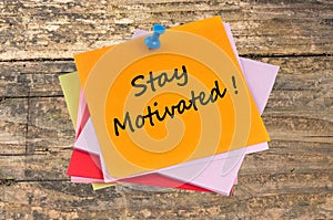 Stay Motivated written on a pushpin paper close-up on a wooden background