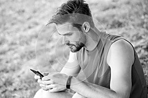 Stay online and available. Sportsman text sms on fresh air. Man relax with smartphone on green grass. Summer activity