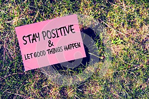 Stay positive and good things happen message written on paper on grass background. Inspirational quote for motivation, happiness