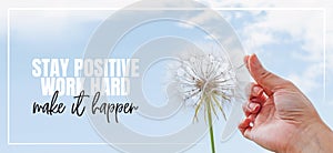 Stay positive, work hard, make it Happen. Hand holding Dandelion flower pointing to blue sky, close up photography, banner design