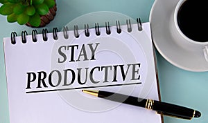 STAY PRODUCTIVE - word in a white notebook on a mint background with a cup of coffee