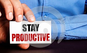 STAY RODUCTIVE is written on a white business card in a man`s hand. Advertising concept