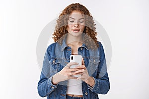 Stay still one more shot. Focused cute hipster redhead girl freckles holding smartphone look carefully phone display