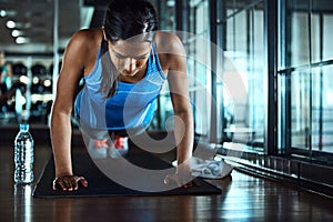 Stay strong. an attractive young woman doing pushups as part of her workout in the gym.