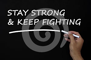 Stay strong and keep fighting text written on blackboard using chalk.