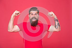 Always stay strong. Strong hipster flex arms red background. Bearded man show physical strength. Building strong biceps