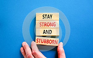 Stay strong and stubborn symbol. Concept words Stay strong and stubborn on wooden block. Beautiful blue table blue background.
