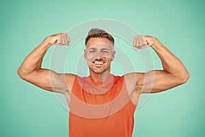 Stay strong in your life. Happy athlete show physical strength. Strong man flex arms blue background. Building strong photo