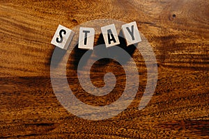 `Stay` text made of wooden cube on  wooden background