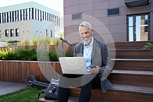 Stay in touch anywhere. Happy mature businessman smiling, making a video call while working on the laptop, sitting