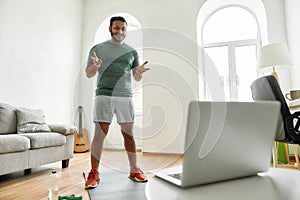 Stay in touch. Full length shot of male fitness instructor greeting viewers while streaming, broadcasting video lesson