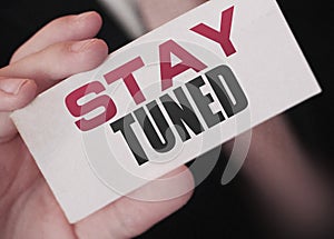Stay tuned words on a card in hand of businessman. Business profit and success concept