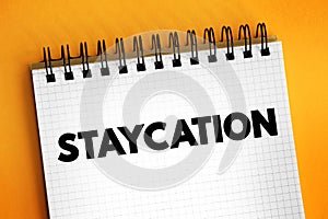Staycation is a spending leisure activities in the local area or at home, text concept on notepad