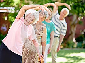 Staying active is key to a healthy retirement. Shot of a group of smiling seniors exercising outside.