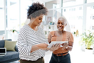 Staying efficient as they drive success into their business. two businesswomen working together on a digital tablet in