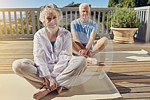 Staying fit and healthy through yoga. Portrait of a senior couple doing yoga together on their patio outside.