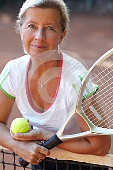 Staying healthy and keeping fit. Attractive senior woman holding a tennis racquet and ball - portrait.