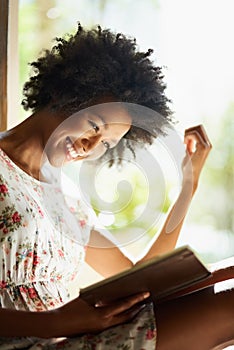 Staying at home with a page turner. a young woman relaxing with a book at home.