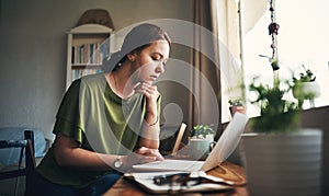 Staying at home, slaying those goals. a young woman using a laptop while working from home.