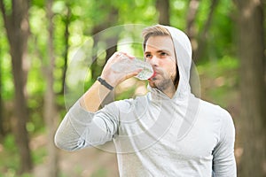 Staying hydrated. Athlete drink water after training in park. care body hydration. sport and health. man in hood drink