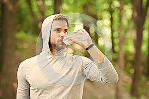 Staying hydrated. Athlete drink water after training in park. care body hydration. sport and health. man in hood drink