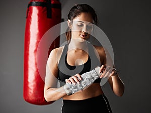 Staying hydrated. an attractive young female boxer drinking water while training in the gym.