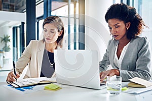 Staying on track with their corporate demands. two corporate businesswomen working together in an office.