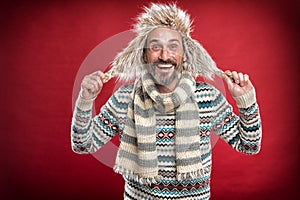 Staying warm. Bearded man accessorizing sweater with hat and scarf. A winter ensemble protects him from cold. Winter