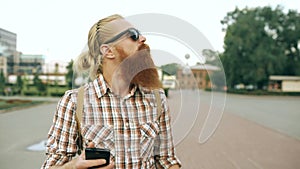 Steadicam shot of Bearded tourist man with backpack walking street and using smartphone for view map outdoors