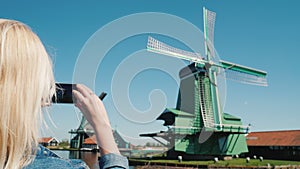 Steadicam shot: woman takes pictures of old windmills in Zaans Schans