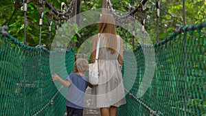 Steadicam shot of a young woman and her son walking on the hanging suspension bridge in the Eco Park in the Kuala Lumpur