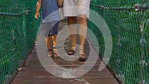 Steadicam shot of a young woman and her son walking on the hanging suspension bridge in the Eco Park in the Kuala Lumpur