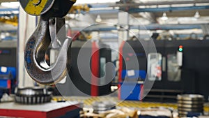 Steady shot of suspended crane working at factory. Metal crane hook hanging Inside Industrial Factory. Plant Interior