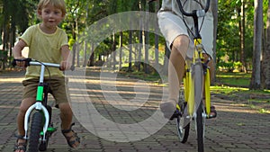 Steadycam shot of a young woman and her little son riding a bicycle and runbike in a tropical park