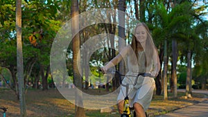 Steadycam shot of a young woman riding a bicycle in a tropical park