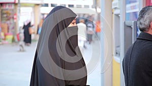 Steadycam - Woman with headscarf, chador using ATM machine, istanbul