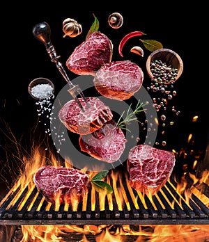 Steak cooking. Conceptual picture. Steak with spices and cutlery under burning grill grate