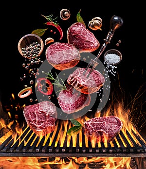 Steak cooking. Conceptual picture. Steak with spices and cutlery under burning grill grate