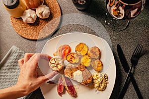 Steak dinner serving. Female hands plating and decorating a special occasion gourmet meal. Filet mignon and baked potatoes with