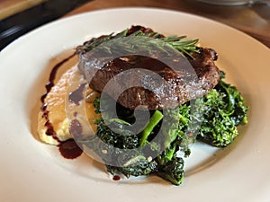 Steak Dinner on White Plate with Broccoli polenta and red wine reduction sauce