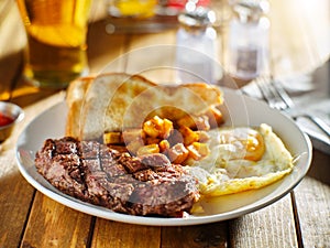 Steak and eggs breakfast with toast and homestyle potatoes in restaurant photo