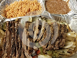 Steak fajita meat with rice and beans in metal container