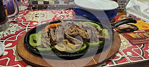 steak fajitas with bell peppers on table in restaurant